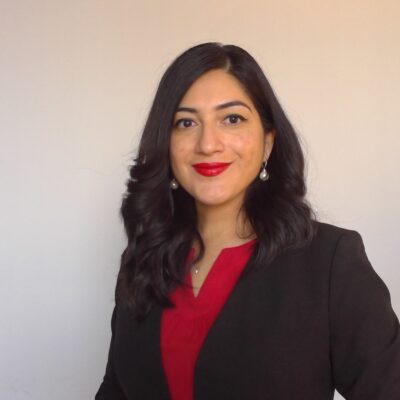 A LatinX women with dark hair and red lipstick wearing a black blazer over a red shirt.