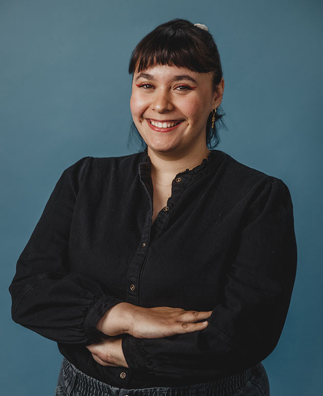 a woman with dark hair wearing a dark shirt with a blue background