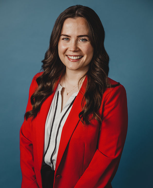 A woman with dark hair wearing a white and black striped shirt under a red jacket.