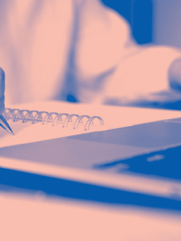 blue and light pink image, close up of a white person writing in notebook and browsing on laptop
