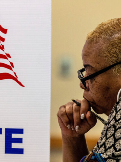 A profile view of a woman in a voting booth.