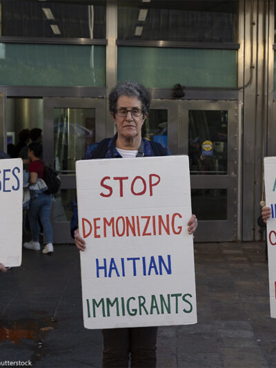 Anti-demonization of immigrants demonstrators hold signs that reads 'NO ONE CHOOSES TO BE A REFUGEE' 'STOP DEMONIZING HAITIAN IMMIGRANTS' 'ACCUSING IMMIGRANTS OF EATING PETS IS AN OLD RACIST LIE.