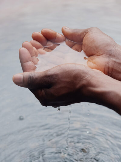Two hands holding water, creating ripples on the surface below.