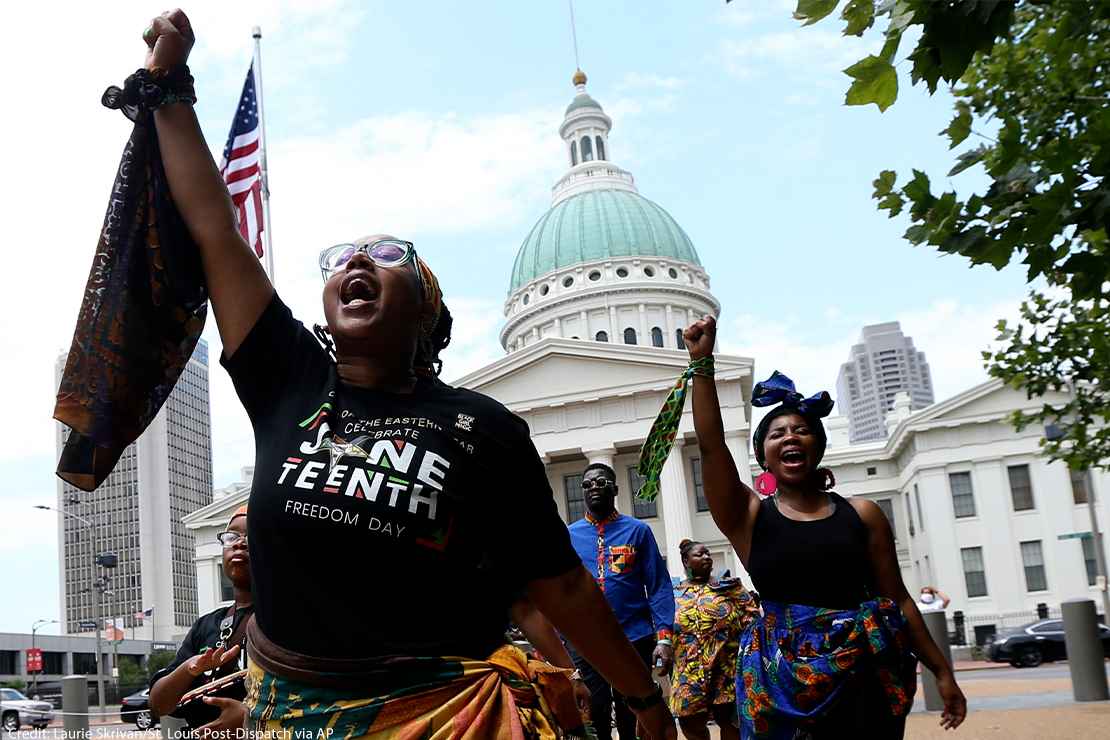 Marchers commemorating Juneteenth walking with fists raised in front of the Old Courthouse in St. Louis.