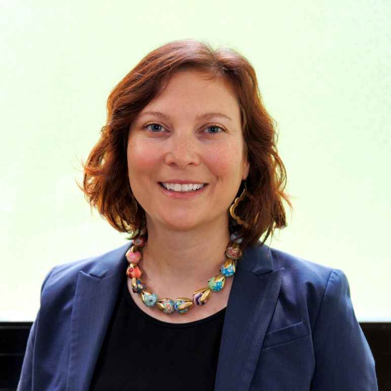 A woman with shoulder length hair wearing a blazer. 