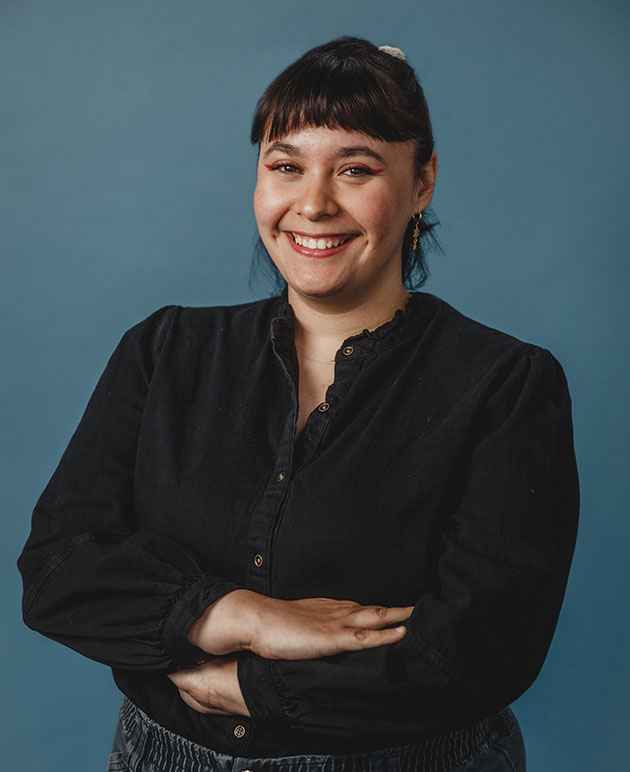 A picture of a woman with dark hair wearing a dark shirt with a blue background