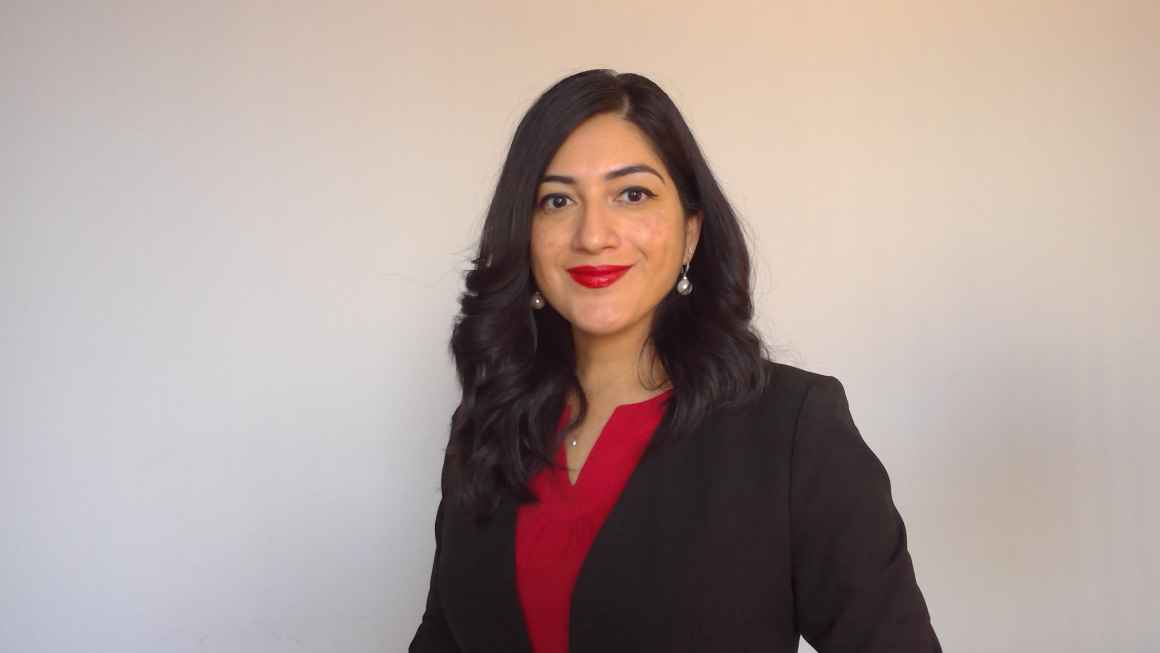 A LatinX women with dark hair and red lipstick wearing a black blazer over a red shirt.
