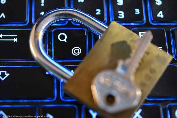A lock and key on top of a computer keyboard.