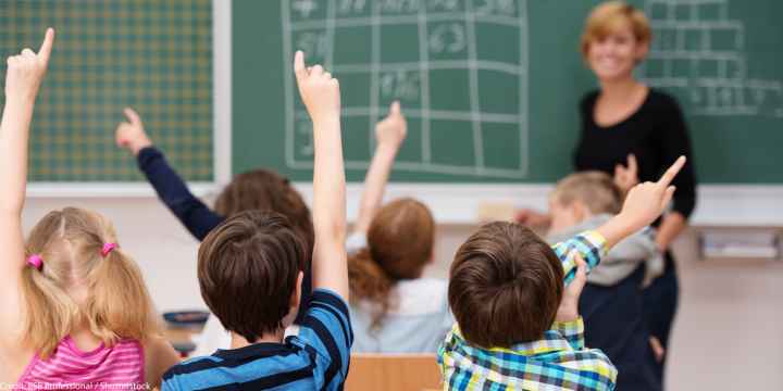 Middle school students raising hands to answer teacher.